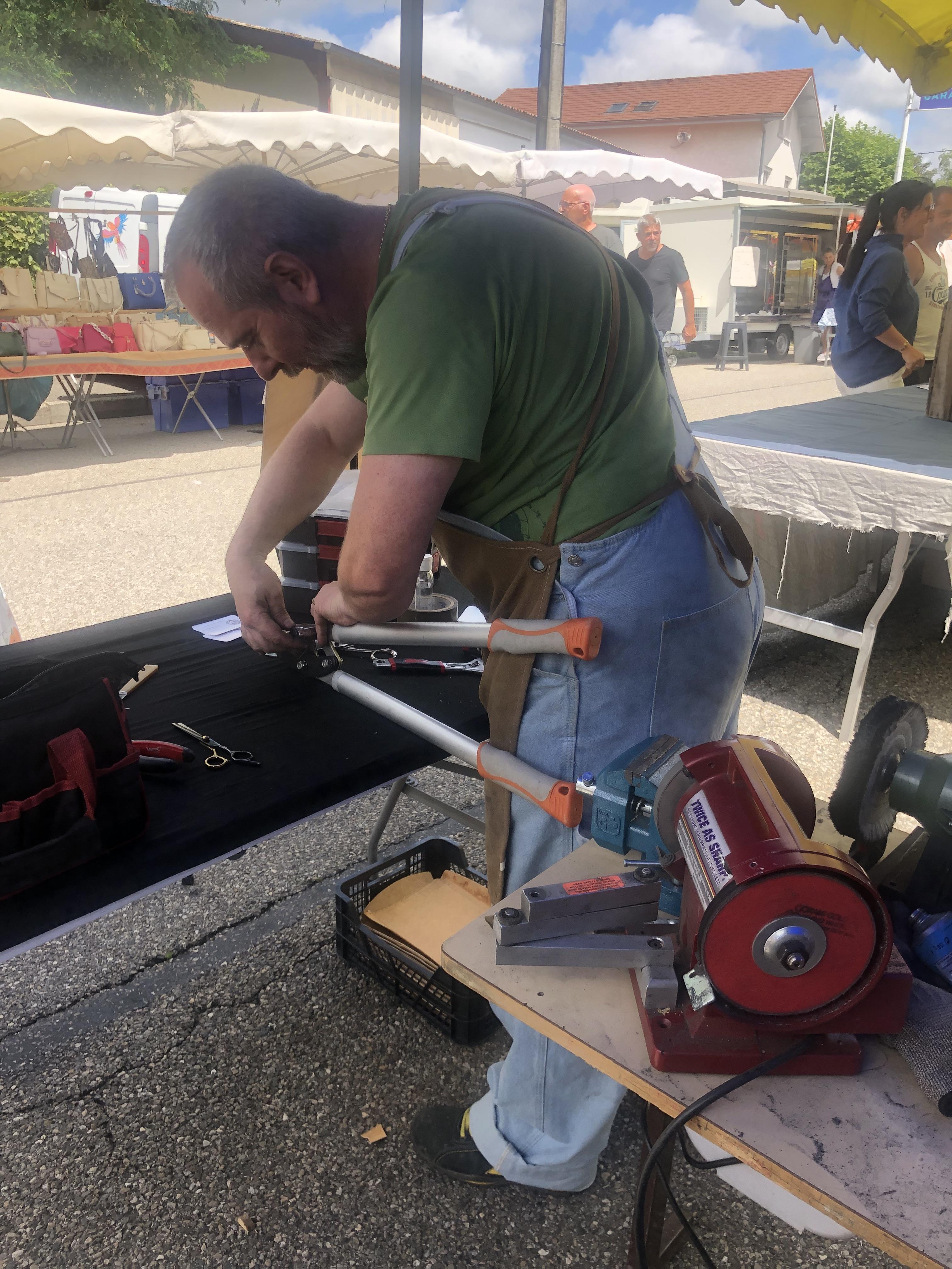 Fabien Azzalin concentré sur l'affûtage d'un sécateur en plein air